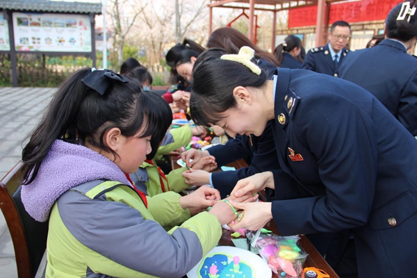 近日，在四川省遂寧市安居區(qū)金雞村兒童之家，重慶市潼南區(qū)稅務(wù)局和四川省遂寧市稅務(wù)局30余名女性職工，為小朋友系上親手制作的手串?？秭z