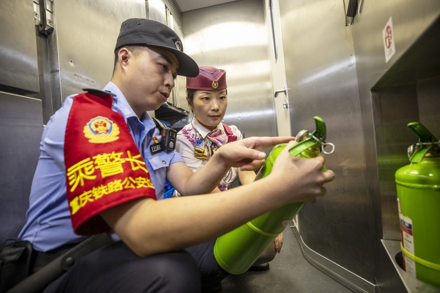 黃同川與列車長一起對餐吧車配備的滅火器進行檢查。胡勇攝