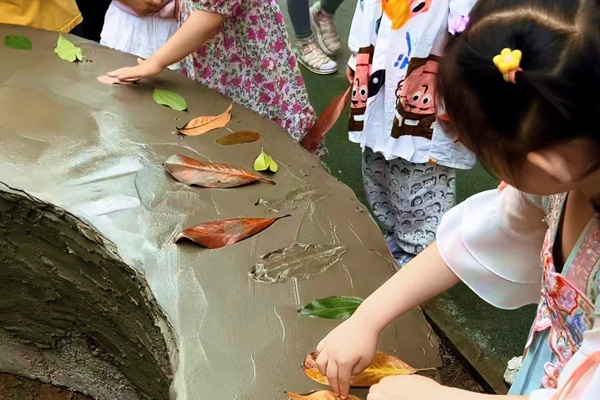 孩子們創(chuàng)作樹葉拓印水泥桌現場。二師附二幼供圖