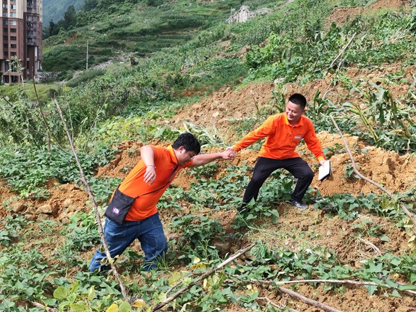 《跋涉》。6月29日，107地質(zhì)隊的駐守地質(zhì)工程師陳虹洲在彭水巡查雨后的地災點時深陷泥潭，同事王發(fā)英搭手拽他脫離“困境”。李明亮攝